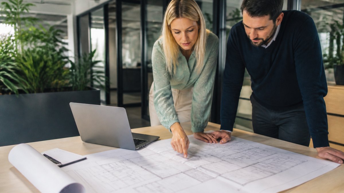 Fire engineer and architect reviewing floor plans for a fire engineering report in a bright office